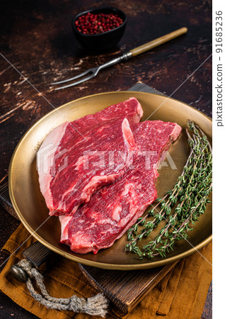 Freah Raw cap rump beef meat steak in a plate with thyme, top sirloin steak. Dark background. Top view 91685236
