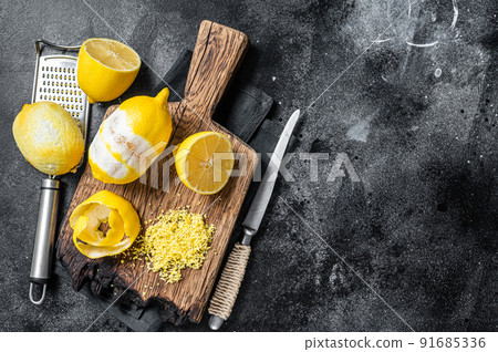 Grated Lemon Zest and spiral peel on wooden board. Black background. Top view. Copy space Grated Lemon Zest and spiral peel on wooden board. Black background. Top view. Copy space 91685336