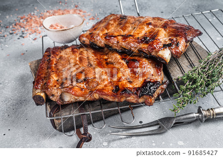 BBQ grilled pork ribs in Barbecue sauce on a grill. Gray background. Top view BBQ grilled pork ribs in Barbecue sauce on a grill. Gray background. Top view 91685427