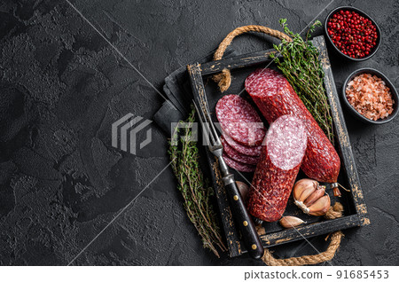Sliced Dry salami sausage with fresh thyme. Black background. Top view. Copy space 91685453
