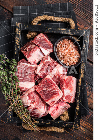 Uncooked Raw diced cubes of lamb meat in wooden tray with salt and thyme. Wooden background. Top view 91685613