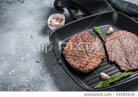 Roasted on grill skillet beef marbled meat steaks. Gray background. Top view. Copy space Roasted on grill skillet beef marbled meat steaks. Gray background. Top view. Copy space 91685626