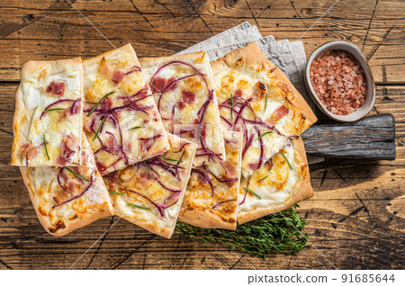 Flammkuchen or tarte flambee with cream cheese, bacon and onions. Wooden background. Top view 91685644