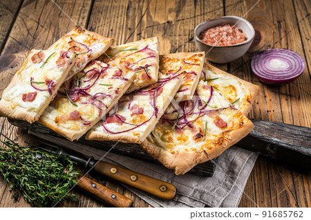 Flammkuchen or tarte flambee with cream cheese, bacon and onions. Wooden background. Top view Flammkuchen or tarte flambee with cream cheese, bacon and onions. Wooden background. Top view 91685762