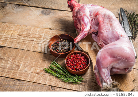 Raw Whole wild hare, fresh game meat on wooden board with herb. Wooden background. Top view. Copy space Raw Whole wild hare, fresh game meat on wooden board with herb. Wooden background. Top view. Copy space 91685843