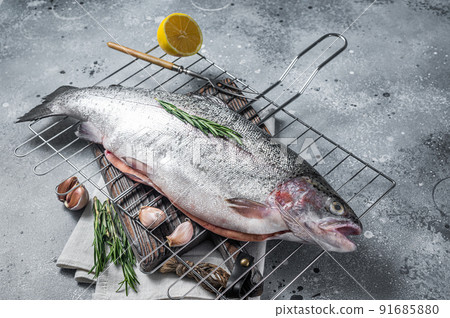 Freshwater trout, fresh raw fish on a grill ready for cooking. Gray background. Top view Freshwater trout, fresh raw fish on a grill ready for cooking. Gray background. Top view 91685880