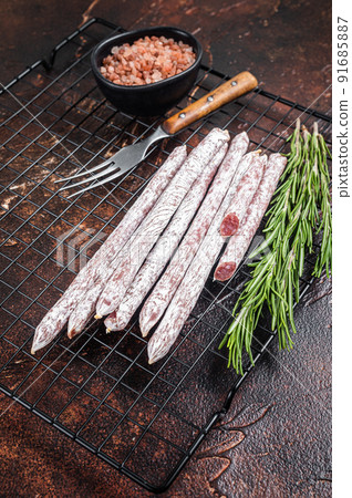 Fuet Catalan dry sausages with rosemary. Dark background. Top view Fuet Catalan dry sausages with rosemary. Dark background. Top view 91685887