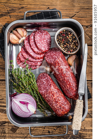 Italian Sliced Dry salami sausage in steel tray. Wooden background. Top view 91685957