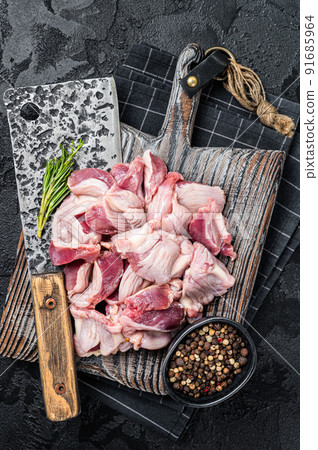 Raw chicken stomachs, giblets gizzards on a butcher board with meat cleaver. Black background. Top view Raw chicken stomachs, giblets gizzards on a butcher board with meat cleaver. Black background. Top view 91685964