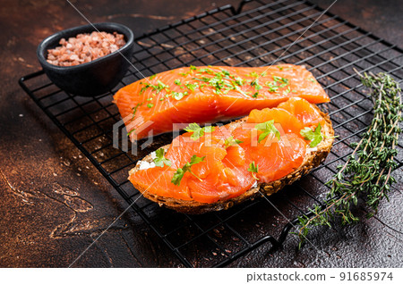 Open sandwich toast with cold smoked salmon fillet, spices. Dark background. Top view 91685974