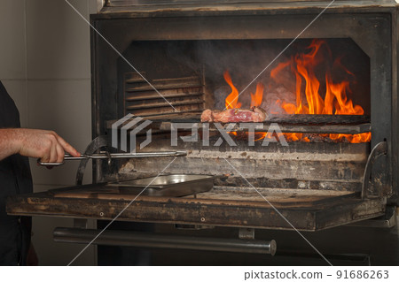 Chef makes beef steak on open fire in restaurant Chef makes beef steak on open fire in restaurant 91686263