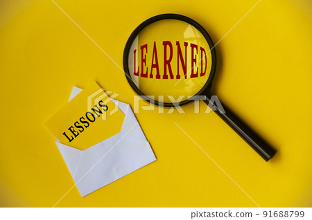 Top view of lessons learned text on envelope and magnifying glass. Learning concept 91688799