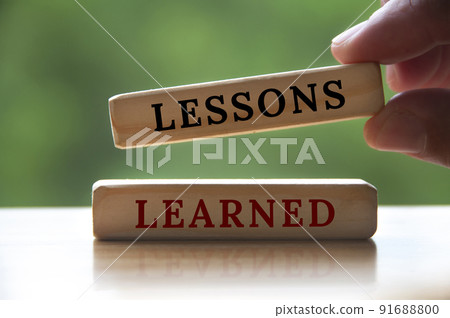 Lessons learned text on wooden blocks with hand holding and blurred nature background. Learning concept 91688800