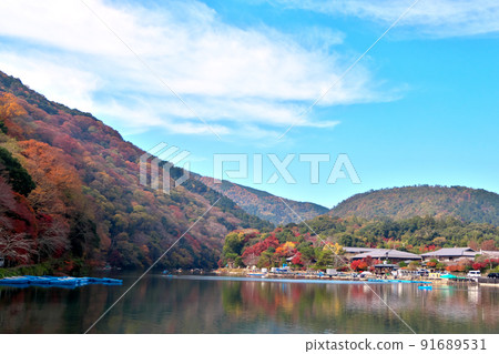 秋天的嵐山樹木的顏色在桂川平靜的水面上熠熠生輝。 91689531