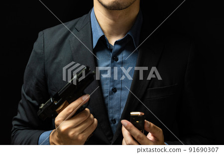 A person in a suit holding a pistol 91690307