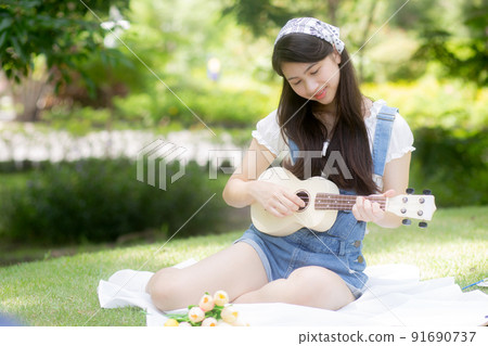Happiness young asian woman sitting and playing ukulele while relaxation for entertainment is hobby. 91690737