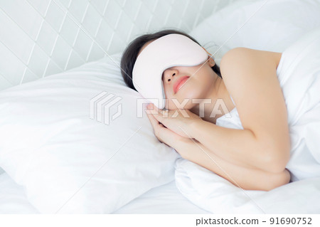 Beautiful young asian woman wearing cover eye and sleeping on bed with head on pillow comfort. 91690752