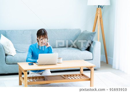 Woman with glasses using a laptop in the living room 91693910