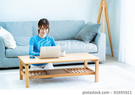 Woman with glasses using a laptop in the living room 91693921