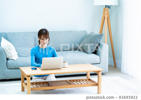 戴眼鏡的女人在客廳裡使用筆記本電腦 91693922