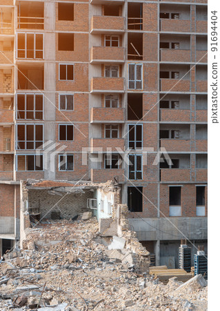 demolition of old building near new construction of modern skyscraper 91694404