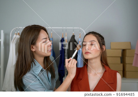 Professional make up artist using a dry powder cosmetic applying on young beautiful woman client close up. Makeup artist using professional makeup brush apply on woman face. Professional make up artist using a dry powder cosmetic applying on young beautiful woman client close up. Makeup artist using professional makeup brush apply on woman face. 91694485