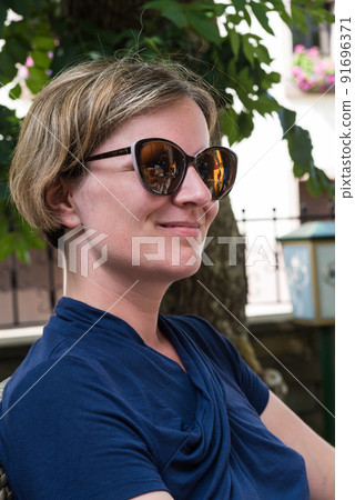 Portrait of a happy 30 yo white girl sitting on a terrace in summer 91696371