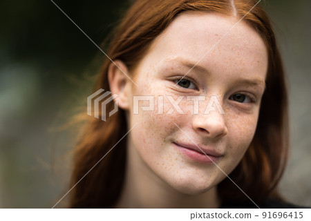 Red haired twelve year old girl with freckles posing with a city bokeh background 91696415