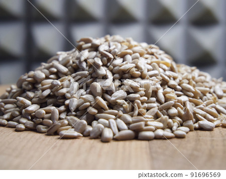 A pile of peeled sunflower seeds on a wooden surface, macro shot. A pile of peeled sunflower seeds on a wooden surface, macro shot. 91696569
