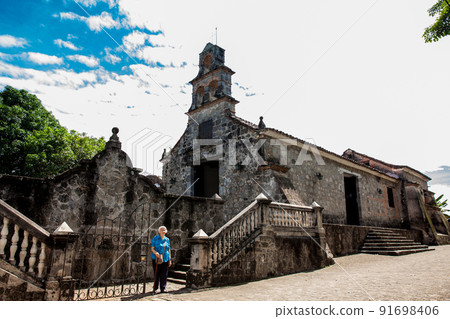 Senior woman at the beautiful historical church La Ermita built in the sixteenth century in the town of Mariquita in Colombia 91698406