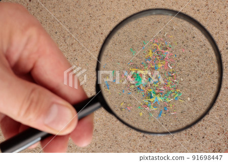 Plastic particles in the sand on the beach, under a magnifying glass. Plastic particles in the sand on the beach, under a magnifying glass. 91698447