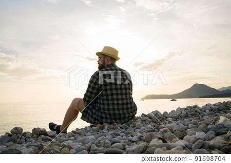 Rear view of man sitting on beach on sunny day outside background - vacation or freelance travel concept Rear view of man sitting on beach on sunny day outside background - vacation or freelance travel concept 91698704