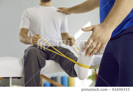 Man doing physical exercises with elastic band at physiotherapy and rehabilitation clinic 91699355
