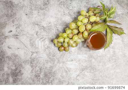 Glass of White Wine or Grape Juice and Branch of Green Grapes on Gray Background 91699874
