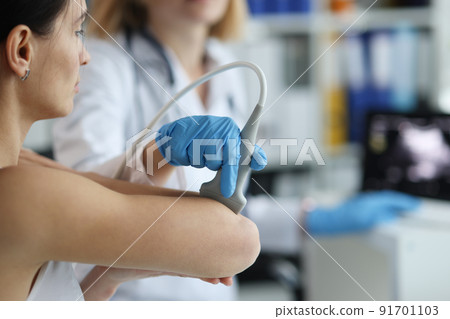 Patient with orthopedic doctor makes ultrasound of elbow joint in clinic Patient with orthopedic doctor makes ultrasound of elbow joint in clinic 91701103