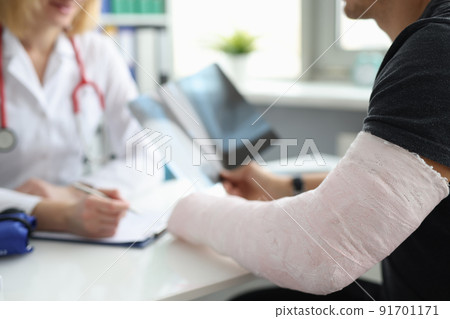 Doctor conducts medical consultation with patient with cast on arm 91701171