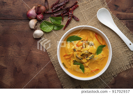 Red Curry with bamboo shoot and green mussel in Coconut Milk soup in white bowl on wood table.Asian food.Top view 91702937