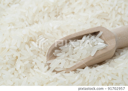 Raw white rice (Uncooked) in wooden scoop on rice grain Raw white rice (Uncooked) in wooden scoop on rice grain 91702957
