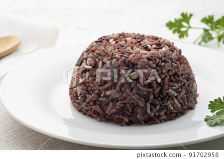 Cooked brown rice or riceberry rice on white plate on wood table Cooked brown rice or riceberry rice on white plate on wood table 91702958