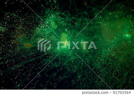 Bright fireworks with a green glowing center with green sparks and smoke flying towards the background of the night sky. High quality photo 91703564