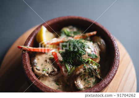 stewed mushroom with cream sauce and green dill in clay bowl on black background 91704262
