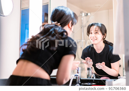 Young woman washing her face in the washroom 91706360