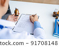 Close-up of doctor's hands writing prescription and holding bottle with pills. Healthcare, medical and pharmacy concept. 91708148