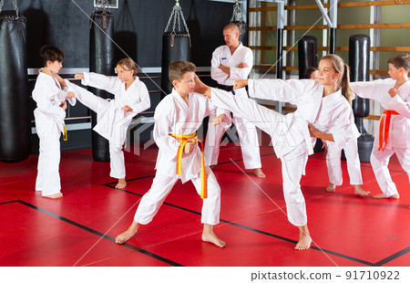 Kids in kimonos exercising techniques in pair during taekwondo class Kids in kimonos exercising techniques in pair during taekwondo class 91710922