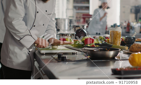 Male cook preparing garlic to add to aromatic food recipe, making delicious meal with fresh ingredients and utensils. Gourmet chef using vegetables to make dish preparations. Handheld shot. 91710958