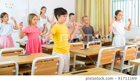 Happy preteen schoolchildren performing physical exercises in class Happy preteen schoolchildren performing physical exercises in class 91711169