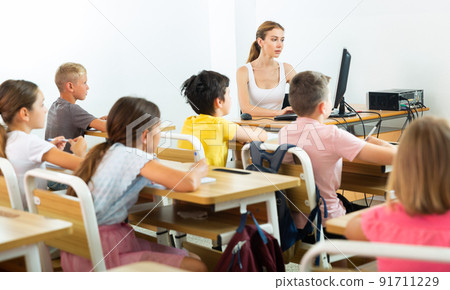 Positive female teacher giving lesson for primary school pupils 91711229