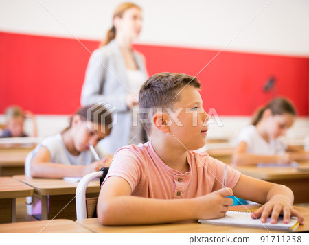 Schoolboy sitting in classroom during lesson in elementary school Schoolboy sitting in classroom during lesson in elementary school 91711258