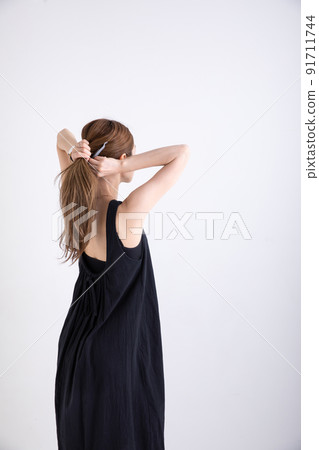 Woman tying her hair Woman tying her hair 91711744