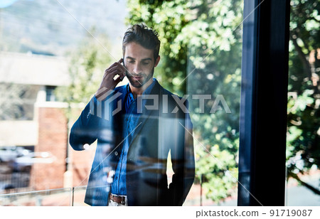 Taking care of business. Shot of a young businessman talking on the phone outside an office. Taking care of business. Shot of a young businessman talking on the phone outside an office. 91719087